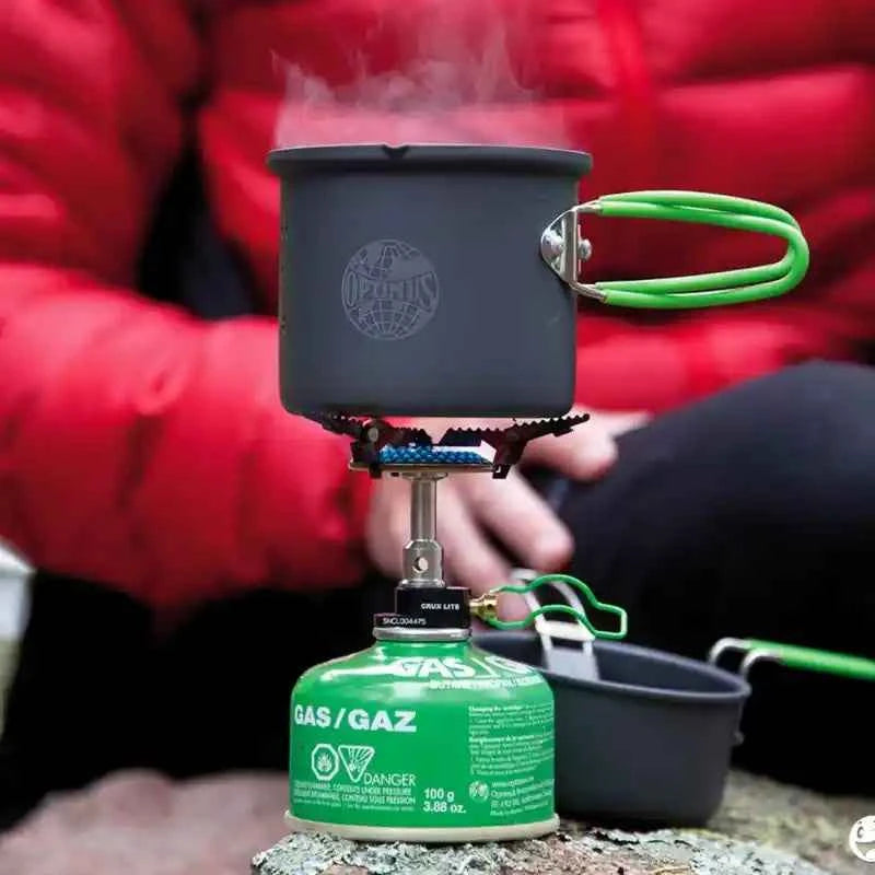 Cartucho de gas Optimus de Mil-Tec de 100g con hornillo encendido calentando una olla de camping.