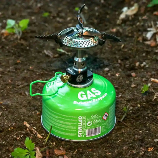 Cartucho de gas Optimus de Mil-Tec de 100g con hornillo portátil acoplado en uso exterior.